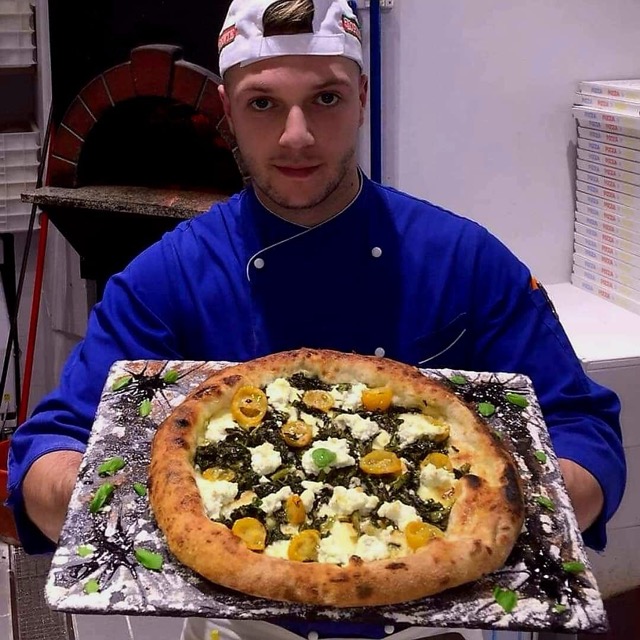 Chef delivering a pizza on traditional stone